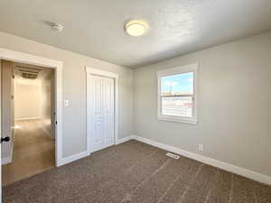 Unfurnished bedroom featuring carpet floors, a closet, and a textured ceiling