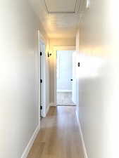 Corridor with a textured ceiling and light hardwood / wood-style floors