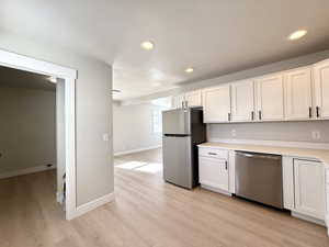 Kitchen featuring white cabinetry, stainless steel appliances, and light wood-type flooring