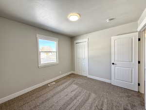 Unfurnished bedroom with carpet, a textured ceiling, and a closet