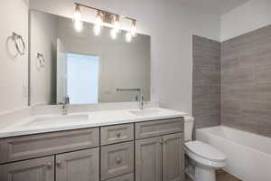 Full bathroom with vanity, tiled shower / bath, and toilet