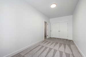 Unfurnished bedroom with light carpet and a closet