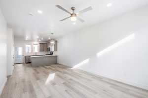 Unfurnished living room featuring ceiling fan and light hardwood / wood-style floors