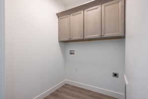 Washroom with cabinets, wood-type flooring, hookup for a washing machine, and electric dryer hookup