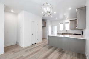 Kitchen featuring decorative light fixtures, sink, stove, light hardwood / wood-style floors, and kitchen peninsula