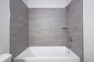 Bathroom with toilet and tiled shower / bath