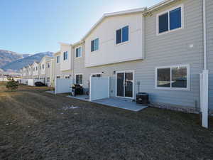 Rear view of house with a mountain view, a lawn, central AC unit, and a patio area