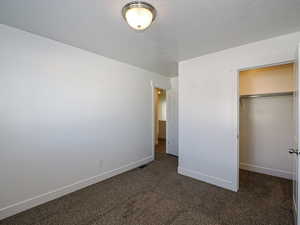 Unfurnished bedroom with dark carpet and a closet