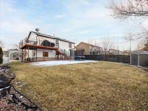 Rear view of house with a storage shed, central AC unit, a trampoline, a large fenced yard and view of wraparound deck