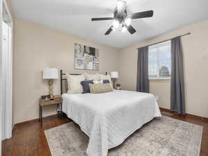 Primary bedroom featuring dark wood-type flooring, walk-in closet and ceiling fan