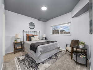 Family room set up as a large bedroom featuring light colored carpet