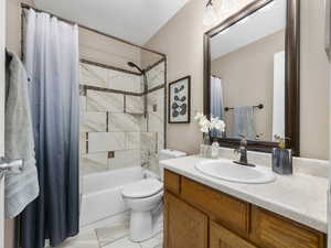 Full bathroom featuring vanity, shower / bath combination with curtain, and toilet