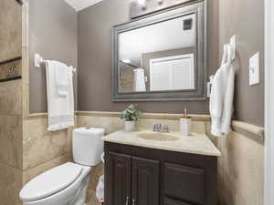 Bathroom with vanity, toilet, and walk-in shower with tile walls