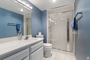 Guest bathroom with tile patterned flooring, vanity, an enclosed shower, and toilet