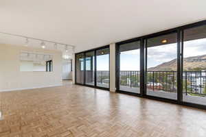 Unfurnished room featuring a wall of windows, light parquet flooring, and a mountain view