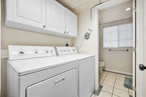 Washroom featuring cabinets, washing machine and dryer.