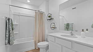 Full bathroom featuring hardwood / wood-style flooring, vanity, shower / tub combo with curtain, and toilet