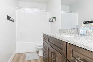 Full bathroom featuring hardwood / wood-style flooring, vanity, toilet, and shower / bath combination with curtain