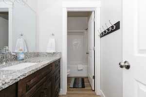 Full bathroom with vanity, hardwood / wood-style flooring, shower / bath combination with curtain, and toilet