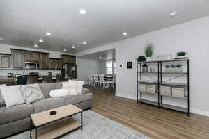 Living room with light hardwood / wood-style floors and a textured ceiling