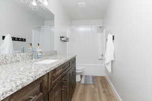 Full bathroom with shower / tub combo with curtain, vanity, toilet, and hardwood / wood-style floors