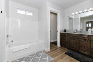 Bathroom with a healthy amount of sunlight, wood-type flooring, a bathtub, and vanity