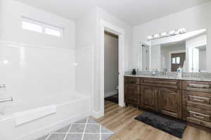 Bathroom with wood-type flooring, toilet, vanity, and a washtub