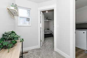 Hallway featuring washer / clothes dryer and light carpet