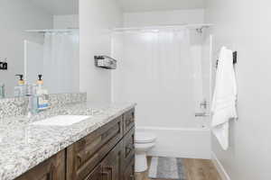 Full bathroom with hardwood / wood-style flooring, vanity, toilet, and shower / bath combination with curtain