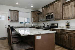 Kitchen featuring dark brown cabinets, a kitchen island, and appliances with stainless steel finishes