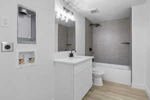 Full bathroom with toilet, tiled shower / bath, a textured ceiling, vanity, and hardwood / wood-style flooring