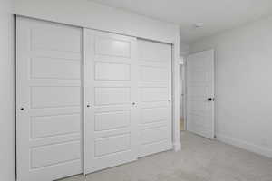 Unfurnished bedroom with light colored carpet and a closet