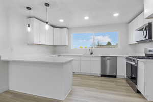 Kitchen featuring stainless steel appliances, white cabinetry, sink, and kitchen peninsula