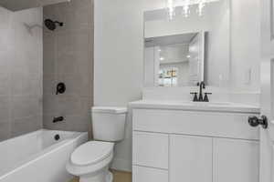 Full bathroom featuring tiled shower / bath combo, vanity, and toilet