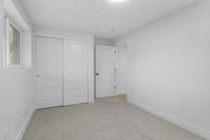 Unfurnished bedroom with light colored carpet and a closet