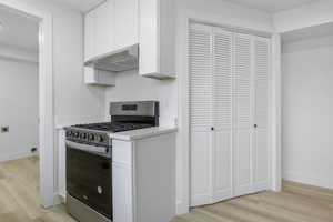 Kitchen with white cabinetry, stainless steel gas range oven, and light wood-type flooring