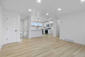 Unfurnished living room featuring sink and light hardwood / wood-style floors