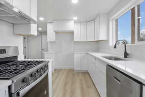 Kitchen featuring white cabinetry, sink, light wood-type flooring, and appliances with stainless steel finishes