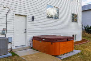 Entrance to property featuring a hot tub and central AC