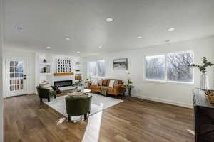 Living room with dark wood-type flooring, built in features, and a textured ceiling