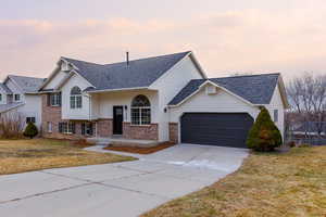 View of front of property featuring a garage and a yard