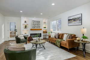 Living room with wood-like flooring, a fireplace, and built in shelves