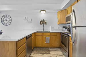 Kitchen featuring stainless steel appliances, sink, light hardwood / wood-style floors, and kitchen peninsula