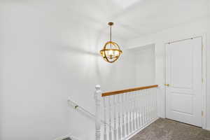 Stairway featuring carpet and a notable chandelier