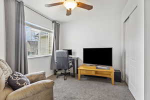 Carpeted office featuring ceiling fan