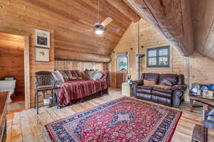 Bedroom with hardwood / wood-style floors, wooden ceiling, high vaulted ceiling, and wood walls