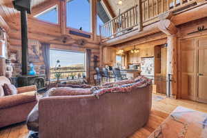 Living room featuring beamed ceiling, a wood stove, wooden ceiling, and light hardwood / wood-style floors