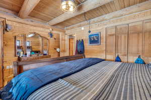 Unfurnished bedroom featuring wood walls, beam ceiling, and wooden ceiling