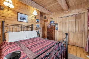 Bedroom with beamed ceiling, wood-type flooring, wooden ceiling, and wood walls