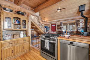 Kitchen featuring a wood stove, tile counters, ceiling fan, light hardwood / wood-style floors, and stainless steel appliances